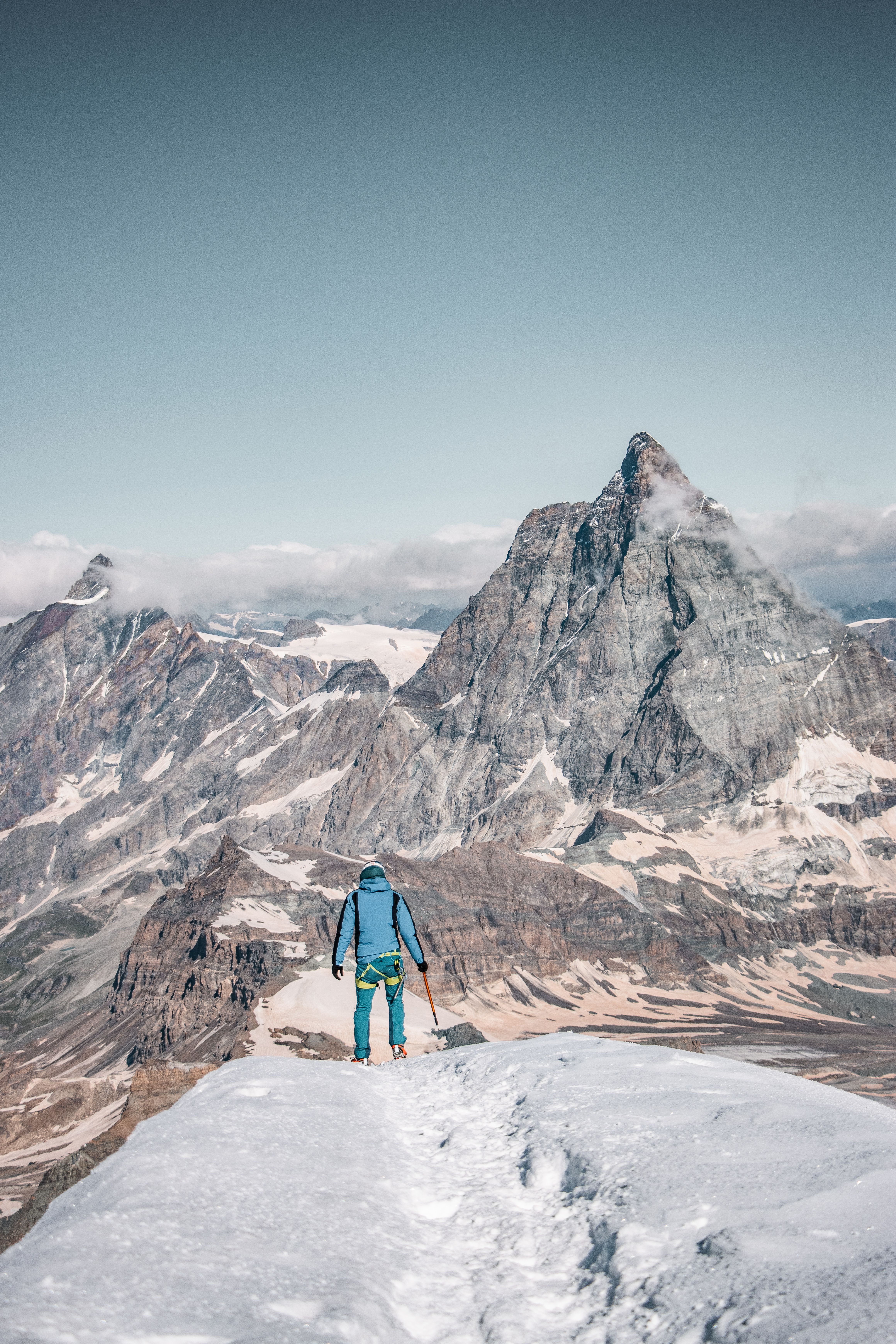 Bergsteiger mit Eispickel beim Aufstieg auf einem schneebedeckten Alpengipfel